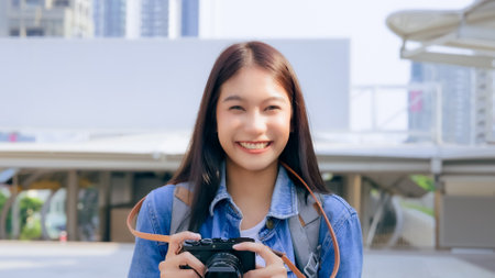 Young asian woman smiling and looking at camera, tourist female using camera vintage with backpack