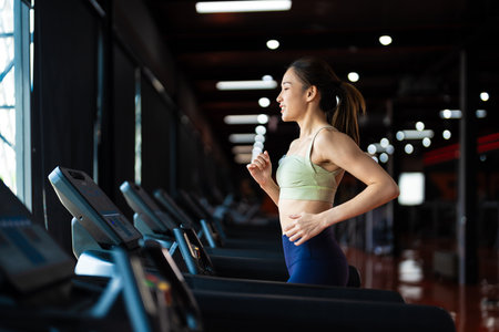 Young Asian Woman Running on Treadmill - Fitness Gym Exerciseの写真素材