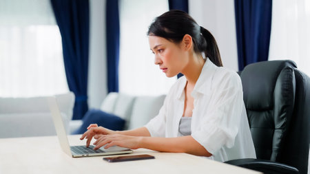 Beautiful young asian woman in casual clothing using computer laptop while working indoorsの写真素材