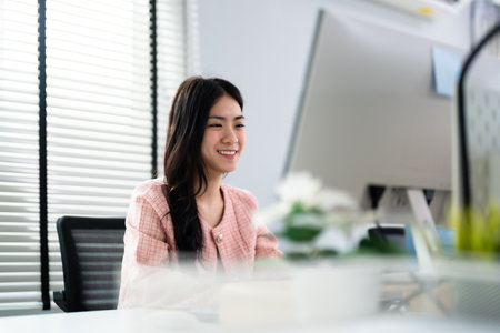 Portrait of attractive young Asian businesswoman smiling in office on desk workspace. Beautiful woman confident. Emotions happy. business workerの写真素材