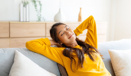 Happy Asian woman relaxing on the sofa at home - Smiling adorable girl enjoying day off lying on the couch, Healthy life style conceptの写真素材