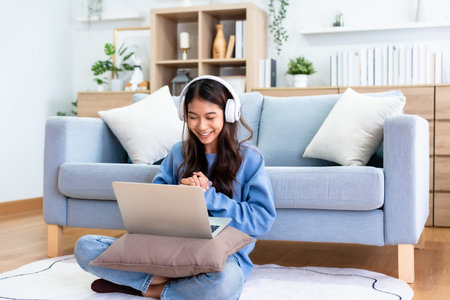 Young Asian Woman Having a Video Call on Laptop in a Cozy Home Office - Remote Work and Technology Conceptの写真素材