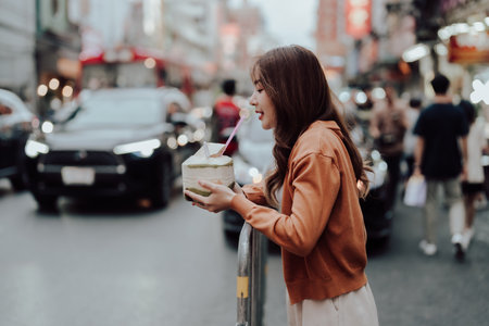 Young asian woman traveller standing and drinking coconut water. Beauty traveller female in city lifestyle chinatown street food market Bangkok, Thailandの写真素材