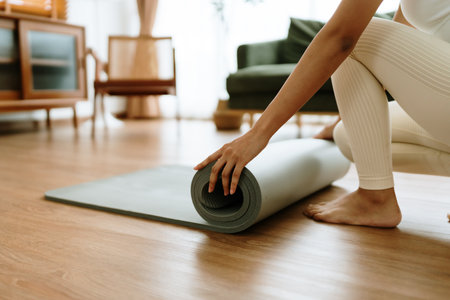 Young Asian woman doing yoga, twisting on a mat in the living room at homeの写真素材