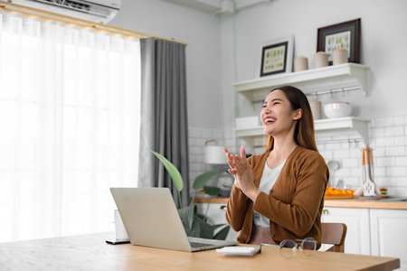 Funny euphoric young asian woman celebrating winning or getting ecommerce shopping offer on computer laptop. Excited happy girl winner looking at notebook celebrating successの写真素材
