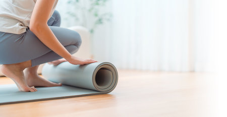 Young Asian woman doing yoga, twisting on a mat in the living room at homeの写真素材