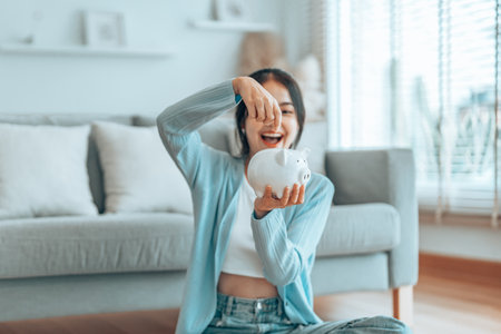 Young Asian woman putting coin in piggy bank. Save money and financial investmentの写真素材