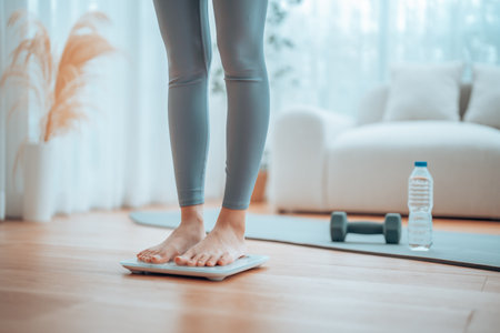Closeup of feet, Young Asian woman standing on scales to measure her weight at home, Checking result...