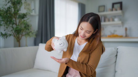 Young Asian woman putting coin in piggy bank. Save money and financial investmentの写真素材