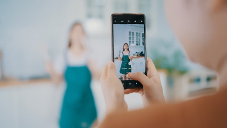 Young asian womans shooting together dancing in kitchen at house when making video for social media, stories trendy dance at home make online contentの写真素材