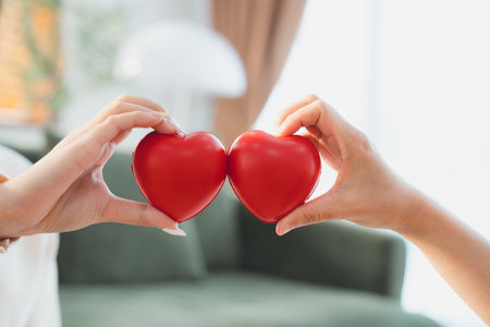 Closeup view of red heart on woman and man hands. Healthy and valentines day conceptの写真素材