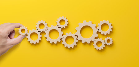 Business process and workflow automation with flowchart. Hand holding wooden cog flowing process management on yellow backgroundの写真素材
