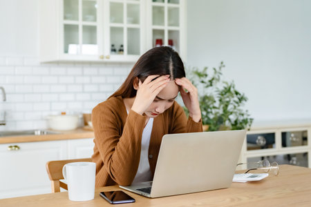 Office syndrome. Overworked tired young asian woman feeling headache, having eyesight problem after computer laptop work. Stressed young woman suffering from fatigue at homeの写真素材