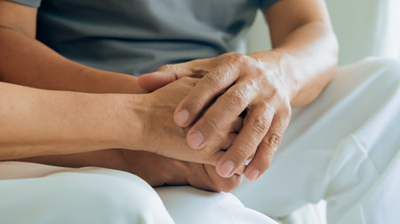 Close up view of caring elderly grandma wife holding hand supporting senior grandpa husband give empathy care love, old married grandparents couple togetherの写真素材