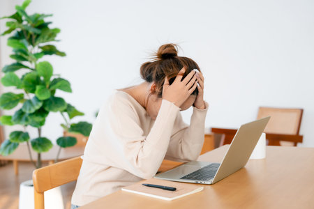 Thoughtful tired woman working on laptop computer looking on screen thinking solving problem at home office, serious woman search for inspiration make decision feel lack of ideasの写真素材