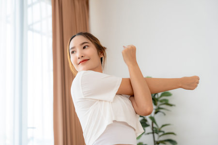 Young Asian woman doing stretch in the morning at home. Health care and body care conceptの写真素材