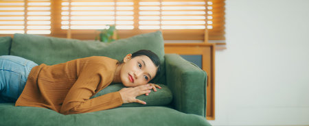 Asian woman resting at home on couch, feeling exhausted after work, lacking energy, or overworked, too tired, and lacking motivationの写真素材