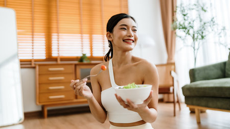 Healthy Asian Woman Enjoying Fresh Salad at Home After Yoga Workoutの写真素材