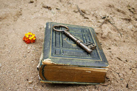 old book and key on sand or beachの写真素材