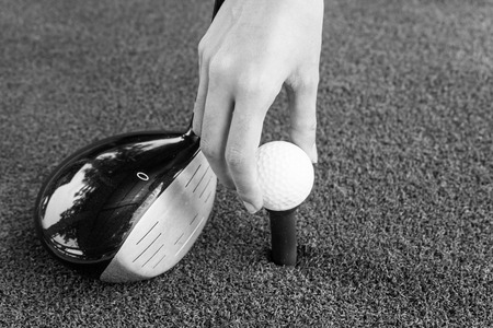 Close-up Hand holding golf ball and a golf wood on a driving rangeの写真素材
