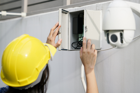 Close Up Of women Technician Fixing CCTV Camera On Wallの写真素材