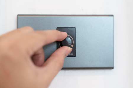 Close up hand turning on grey dimmer switchの写真素材