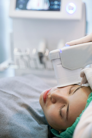 Laser or frequency Skin Tightening Face Lift treatment procedure involves.Young woman receiving laser chin.の写真素材