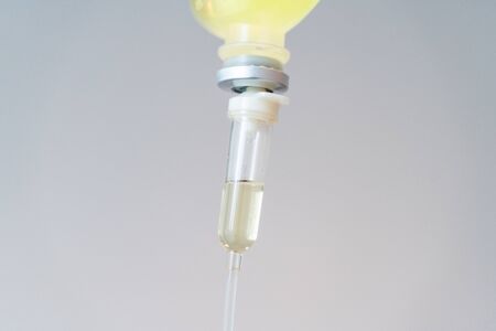 Drop of Saline Solution,IV drip chamber, IV tubing hanging on a metal pole in the roomの写真素材