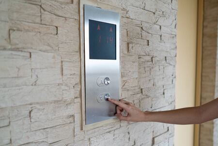 Hand press a button of elevator for lower level floor