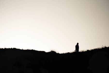 SIlhouette of a people walking at sunset on a hill.の写真素材