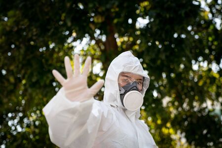 Woman wearing gloves with biohazard chemical protective suit and mask.with unhappy face. Woman holds...