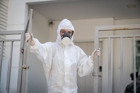 Woman wearing gloves with biohazard chemical protective suit and mask.with unhappy face. Opening an...