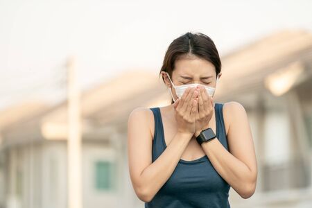 Woman feeling sick, coughing or sneezing. she wearing protective mask.の写真素材