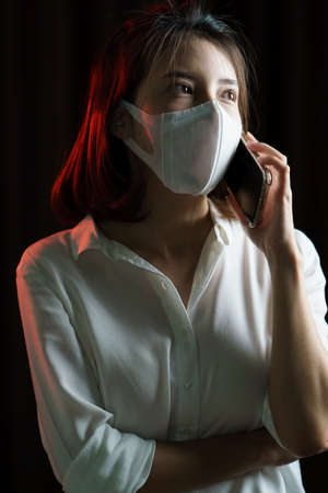 Asian woman wearing surgical face mask  making a phone call.の写真素材