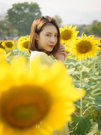 Portrait of a woman with a sunflower on sunflower field.の写真素材