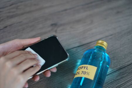 Hand pouring ethyl alcohol from bottle  into a cotton piece for clean mobile phone, corona virus or Covid-19 protection.の写真素材