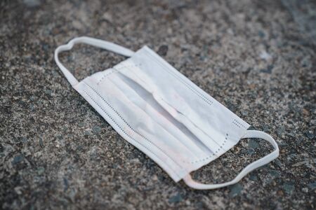 Used dirty face surgical mask dropped on the ground, selective focus center maskの写真素材