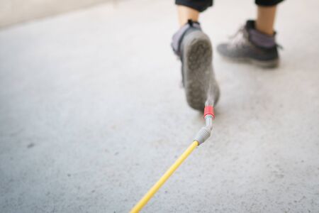 Worker with spray the cleaning sanitize chemical to disinfect COVID-19 virus pathogen on shoes.の写真素材