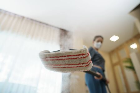 Woman washes the floor with a steam mop.の写真素材