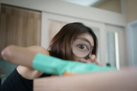 Women with magnifying glass cleaning the table with spray disinfectant for corona virus or Covid-19 protection.の写真素材