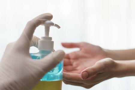 hands using wash hand sanitizer gel pump dispenser. transparent sanitizer in pump bottle, for killing germs, bacteria and virus.の写真素材