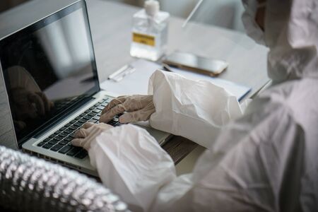 Woman in protective hazmat suit worker  in laboratory computer analyzing in laboratory. to stop...