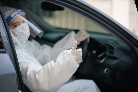 Woman driver with gloves,protective hazmat suit, face shield and mask.
corona virus or Covid-19 protection.の写真素材