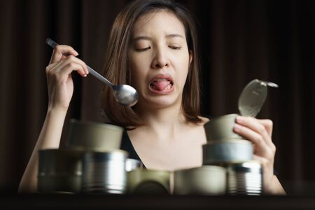 Quarantine time, bored woman eating canned food with group of Aluminium canned food.
