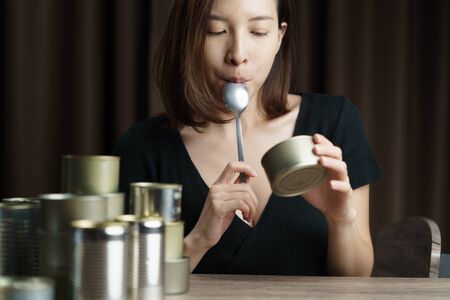 Quarantine time, woman eating canned food with group of Aluminium canned food.