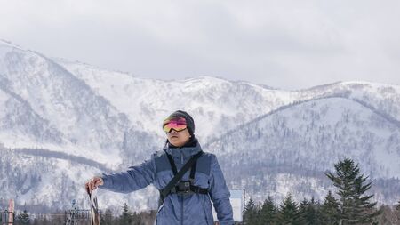 Man with ski in hand wearing ski glasses in snow winter mountain.