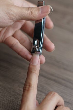 Man using nail clipper clipping her fingernails.
