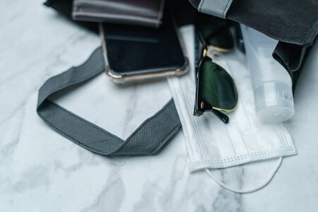 Shopping bag with must have items smart phone, protective face mask, glasses and sanitizer gel, corona virus or Covid-19 protection.の写真素材