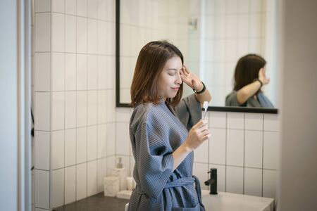 Woman brushing teeth in front of her bathroom mirror.の写真素材