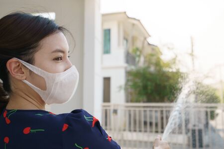 Woman hand holding garden hose spraying water from rubber tube .の写真素材